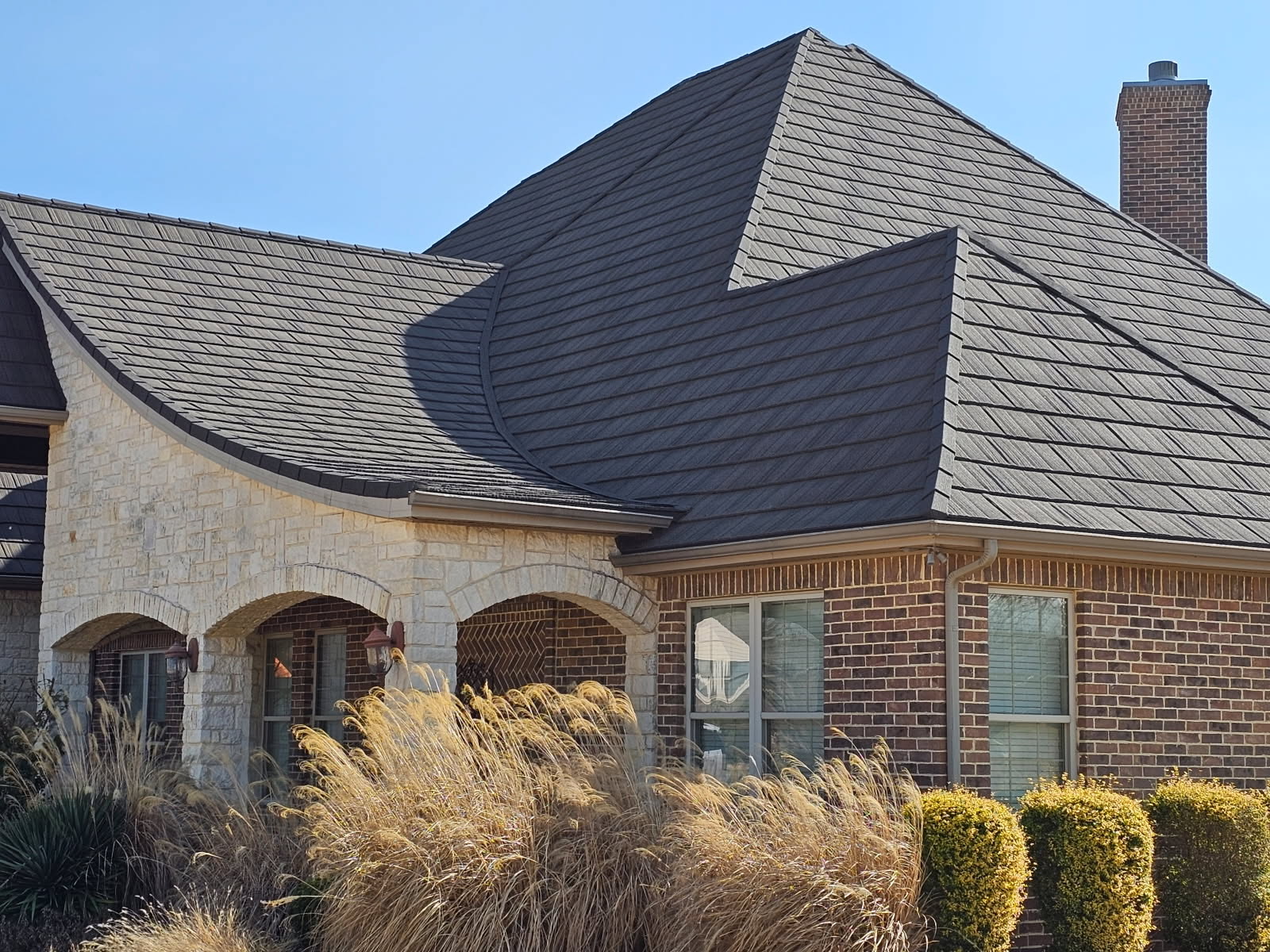 Stone and brick home with a WeatherLok stone-coated steel shake roof